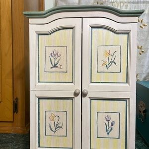 Jewelry cabinet 2 door opens.  Inside is a mirror and shelves. Antique cream.